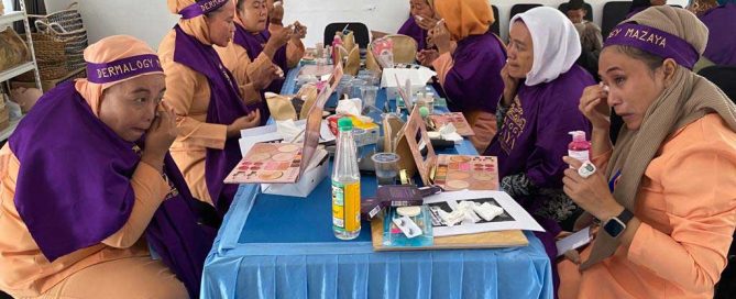 A participant applies makeup with guidance from the training team