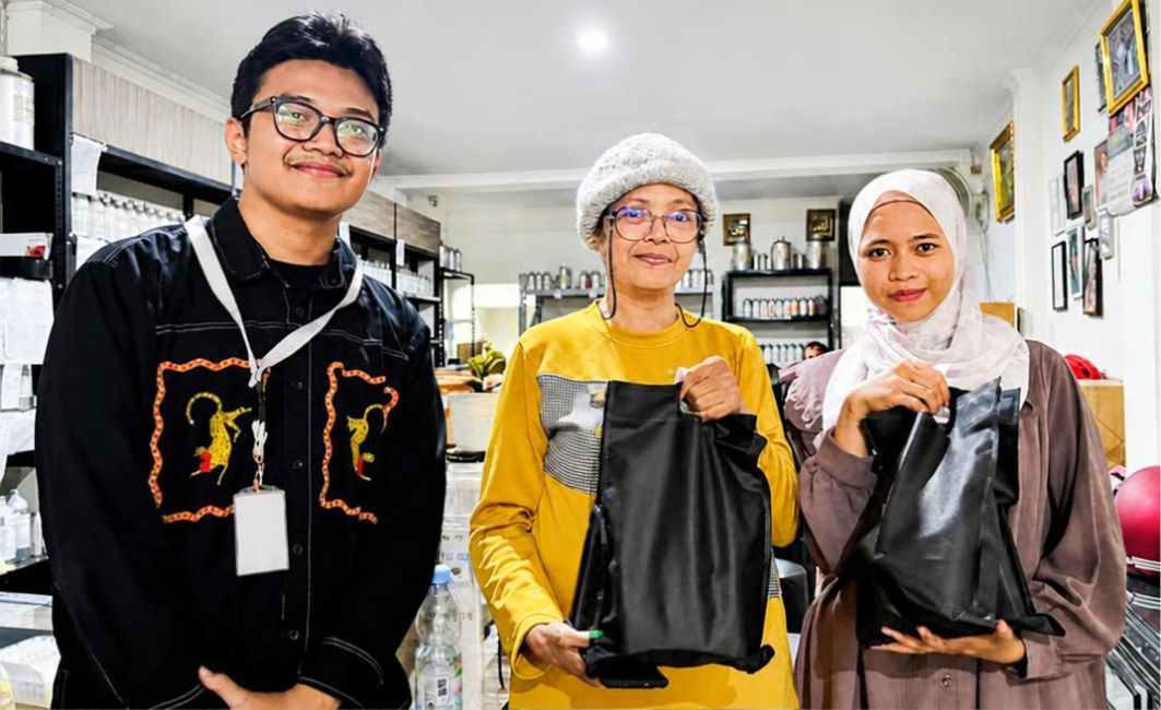 Penyaluran Sarana Produksi Parfum kepada Peserta Perempuan Terpilih Dua peserta perempuan tersenyum memegang kantong bantuan modal usaha wirausaha parfum